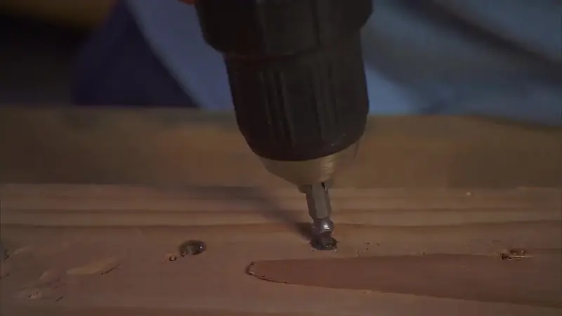 A drill in reverse seating a SpeedOut bit in a stripped screw in a pine board