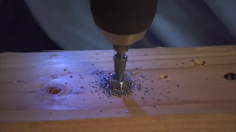 A SpeedOut bit drilling in reverse into a stripped bolt head, metal shavings around it